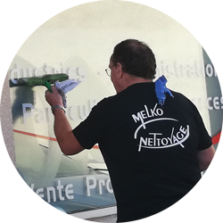 Employé Melko Nettoyage qui nettoie une vitre